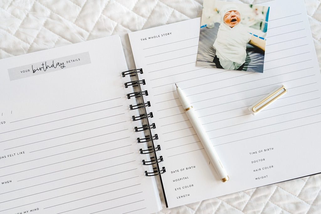 Your birthday details page with prompts for writing about baby's birth inside of pregnancy journal book to track pregnancy week by week with pictures of baby and belly and journaling space sitting on white quilt